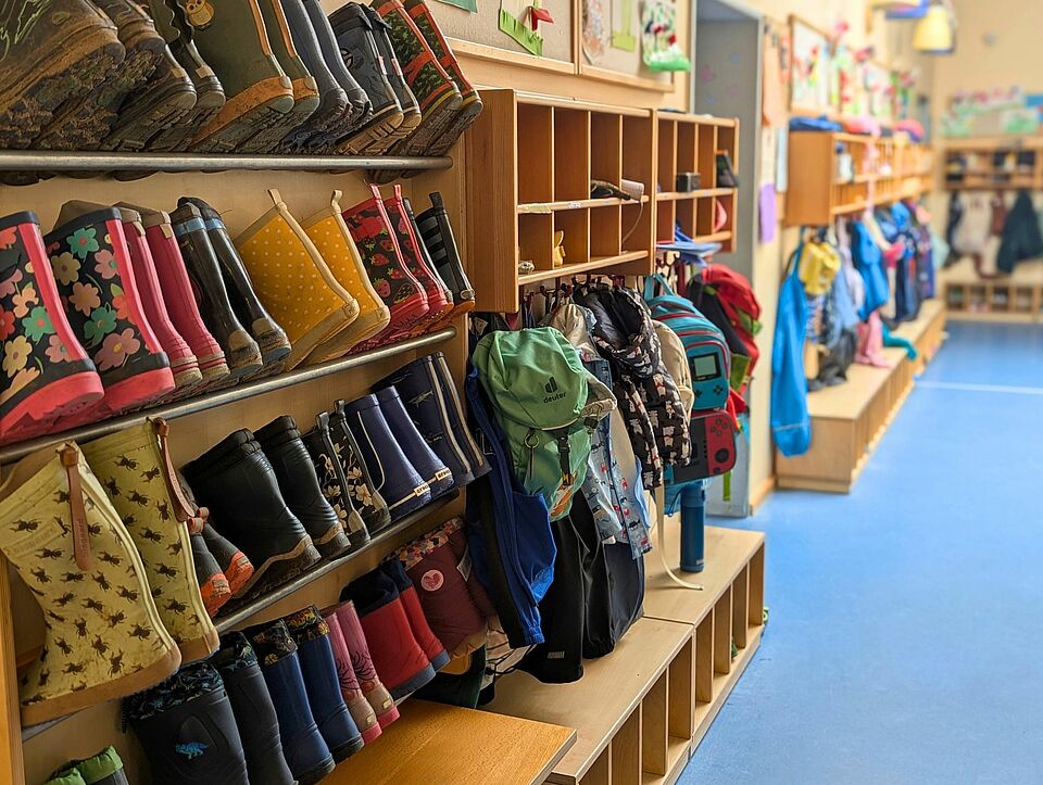 Garderobe der Kita Little Friends  mit zahlreichen Gummistiefeln, Jacken, Rucksäcken uns Schuhen